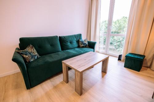 a living room with a green couch and a wooden table at Apartament Miejski Chill in Toruń