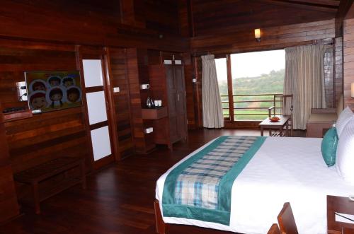 a bedroom with a large bed and a balcony at GReaT Trails Kodaikanal by GRT Hotels in Kodaikānāl