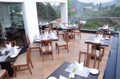 a restaurant with tables and chairs on a balcony at GReaT Trails Kodaikanal by GRT Hotels in Kodaikānāl