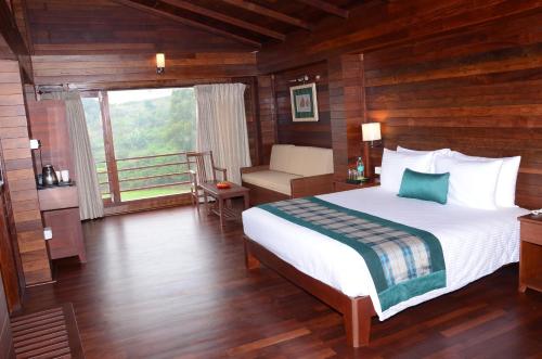 a bedroom with a large bed and a balcony at GReaT Trails Kodaikanal by GRT Hotels in Kodaikānāl