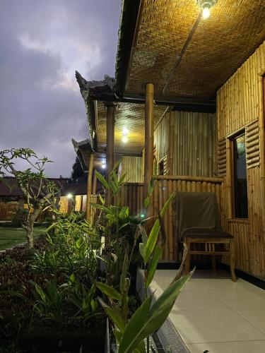 a porch of a house with a chair and plants at D'Yoga Bamboo House in Kintamani