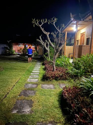 a man walking down a path in a yard at night at D'Yoga Bamboo House in Kintamani