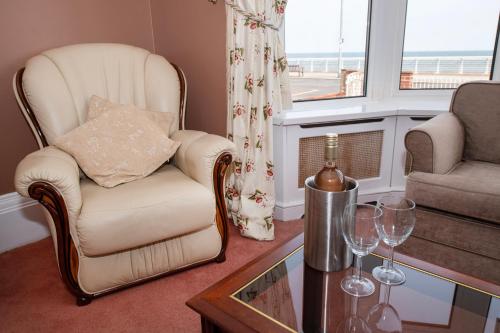 a living room with a chair and a table with wine glasses at The Seacourt in Bridlington