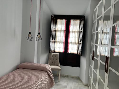 a bedroom with a bed and a chair and a window at Apartment Palacio de Los Vibora Parking Gratis in Lucena