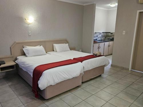 um quarto com uma cama grande e um cobertor vermelho em Pietersburg Lodge em Polokwane