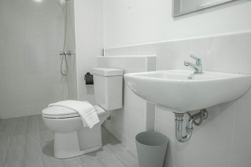 a white bathroom with a sink and a toilet at Ezyinn in Nakhon Sawan