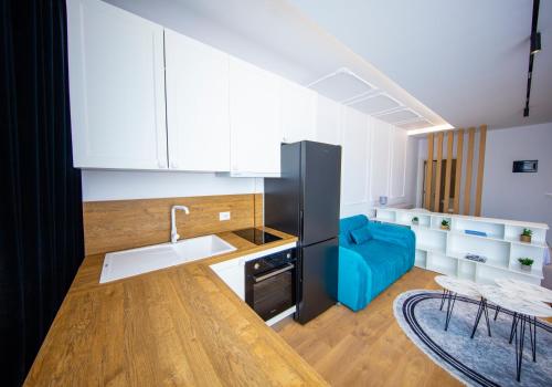 uma cozinha com armários brancos e um sofá azul em Prestige Studio at Komuna e Parisit em Tirana