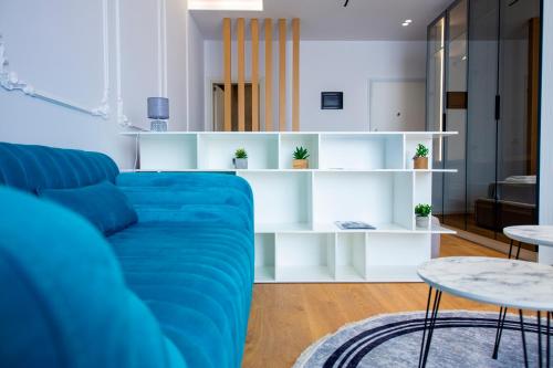 uma sala de estar com um sofá azul e prateleiras brancas em Prestige Studio at Komuna e Parisit em Tirana