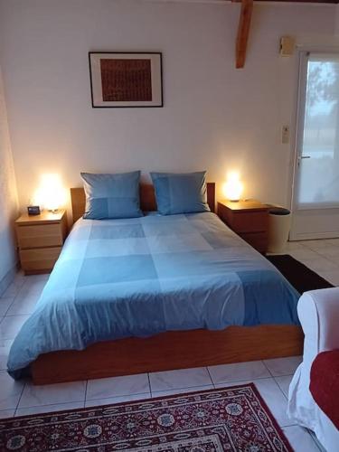 a bedroom with a large bed with blue sheets and two lamps at La petite maison à la campagne / our little house in La Chapelle-Launay