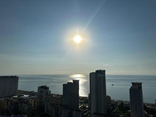 a view of a city with the sun rising over the ocean at Pirosmani Mini Hotel in Batumi