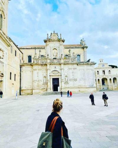 a woman standing in front of a large building at Palazzo dei Gigli Puglia - house with heatable rooftop-Pool in Ugento