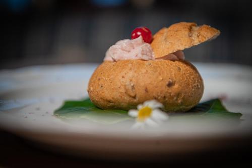 a dessert on a white plate with a cookie and a cherry at Hotel Al Sonnenhof in San Vigilio Di Marebbe