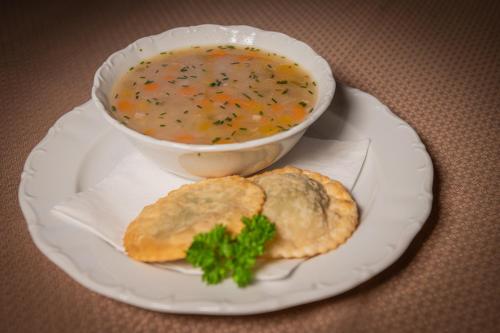 a plate with a bowl of soup and some biscuits at Hotel Al Sonnenhof in San Vigilio Di Marebbe