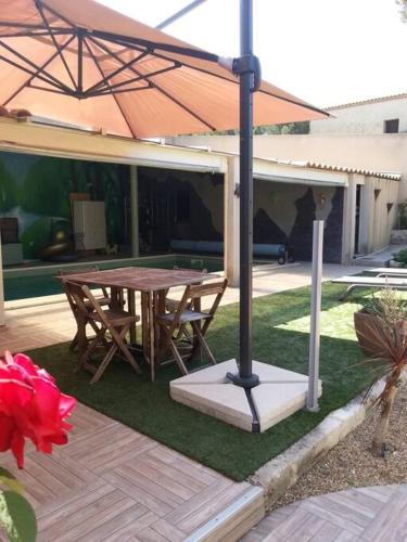 a patio with a wooden table and an umbrella at Maison indépendante climatisée dans quartier calme in Villeneuve-lès-Avignon