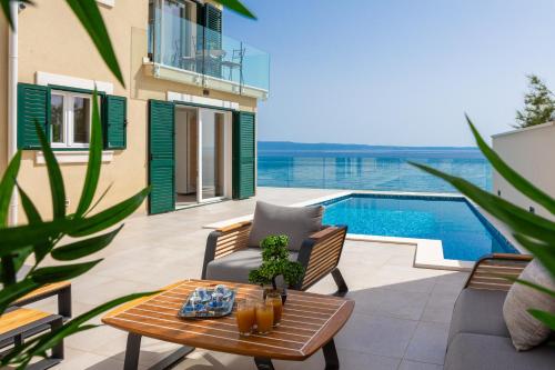 a patio with a table and chairs and a swimming pool at Epetium Beach Villa in Split