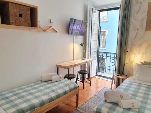 a room with two beds and a desk and a balcony at Estrela Charming Rooms 2 by HOST-POINT in Lisbon