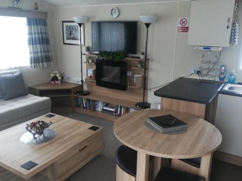 a small living room with a table and a kitchen at Del's den lakeside weeley bridge 2bedroom in Weeley