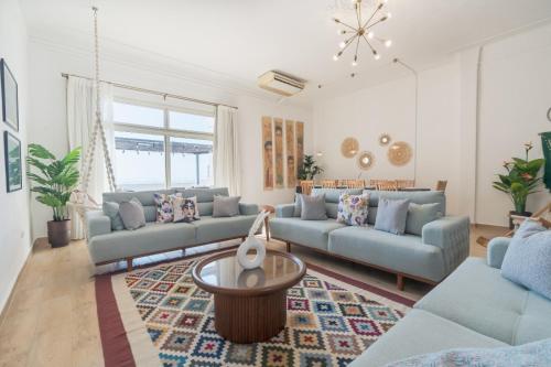 a living room with blue couches and a table at Nabeel Homes - Seaview Rooftop - San Stefano in Alexandria