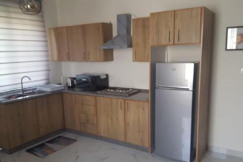 a kitchen with wooden cabinets and a stainless steel refrigerator at Aida's Home-Shmeisani central location near Abdali in Amman