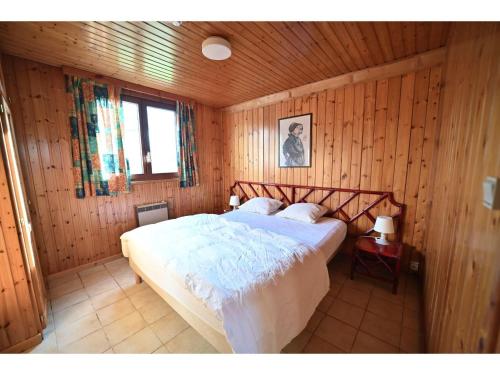 sypialnia z łóżkiem w drewnianej ścianie w obiekcie Cozy Holiday Home in Somme-Leuze with Private Garden w mieście Noiseux