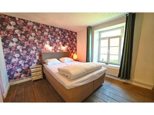 a bedroom with a bed with a floral wallpaper at Stone-built holiday home in Werpin with garden in Werpin