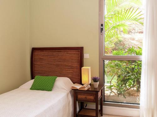 een slaapkamer met een bed met een groen kussen en een raam bij Belvilla by OYO Vibrant Villa with Swimming Pool in Salobre