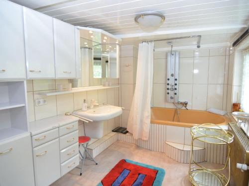 a bathroom with white cabinets and a sink and a tub at Quiet and cosy holiday home in Herzberg in Herzberg am Harz