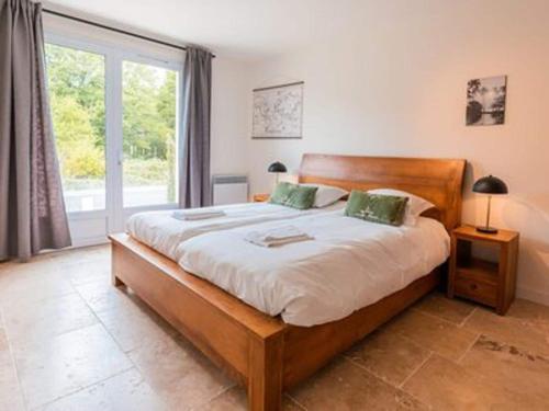 ein Schlafzimmer mit einem Bett und einem großen Fenster in der Unterkunft Spacious and modern villa with large garden and BBQ area in Les Forges