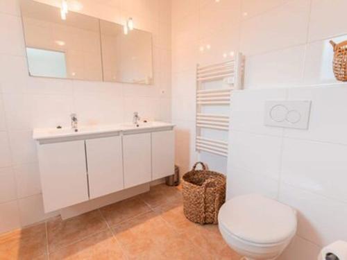 La salle de bains blanche est pourvue de toilettes et d'un lavabo. dans l'établissement Spacious and modern villa with large garden and BBQ area, à Les Forges