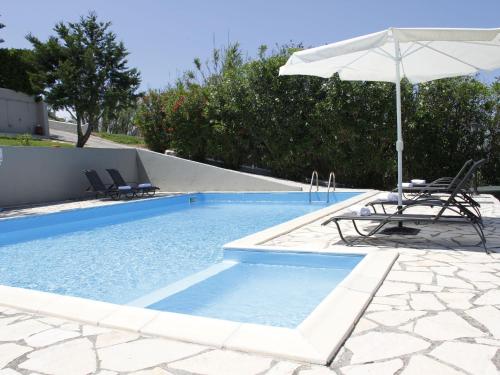 a swimming pool with an umbrella and two chairs and a table and an umbrella at Villa in Corfu with Pool near Gialos Beach in Astrakeri