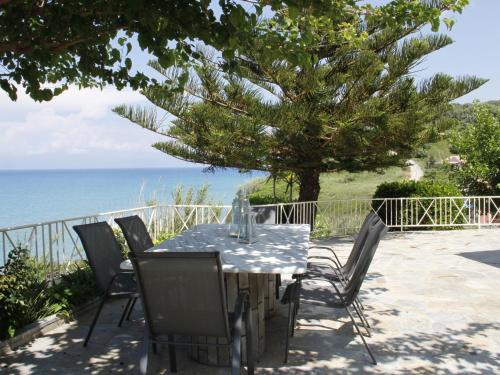 a table and chairs with the ocean in the background at Villa in Corfu with Pool near Gialos Beach in Astrakeri