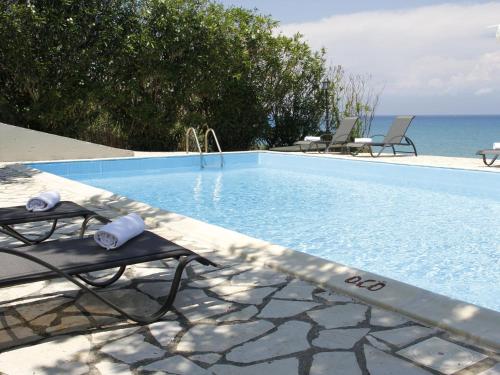 a swimming pool with chairs and the ocean in the background at Villa in Corfu with Pool near Gialos Beach in Astrakeri