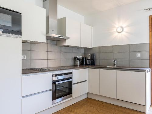 a white kitchen with white cabinets and a sink at Alpine Retreat w Sauna in Abondance