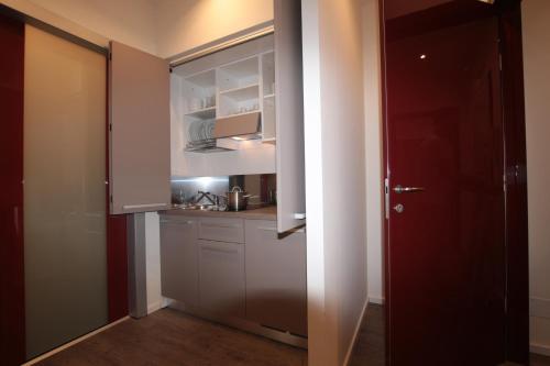a kitchen with white cabinets and a red door at Marcona24 in Milan