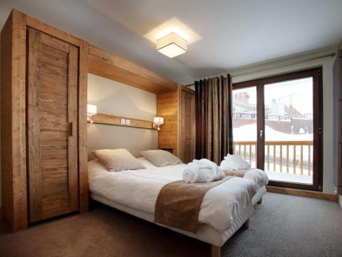 - une chambre avec un lit et une grande fenêtre dans l'établissement Luxury apartment with a balcony in the lively Arc 2000, à Arc 1950