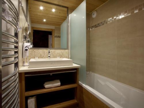 La salle de bains est pourvue d'un lavabo, d'une baignoire et d'un miroir. dans l'établissement Luxury apartment with a balcony in the lively Arc 2000, à Arc 1950