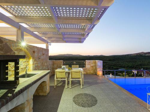 a patio with a table and chairs and a pool at Villas in Crete with Private Pool & Beaches in Achlades