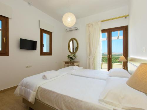 a white bedroom with two beds and a mirror at Villas in Crete with Private Pool & Beaches in Achlades