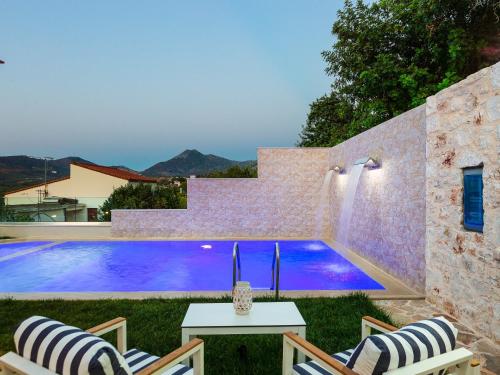 a swimming pool in a yard with two chairs and a table at Villas in Crete with Private Pool & Beaches in Achlades