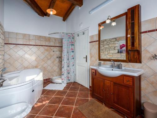 La salle de bains est pourvue d'une baignoire, d'un lavabo et de toilettes. dans l'établissement Beautiful villa with swimming pool and fenced garden, à Tinjan