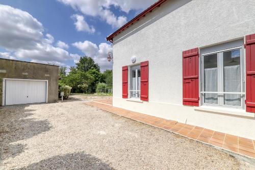 a white building with red shutters and a garage at Maison Jules - 12 min Disneyland - 10 P in Esbly