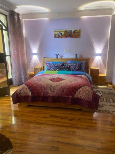 a bedroom with a large bed with purple walls and wooden floors at Kefetew Guest House in Addis Ababa