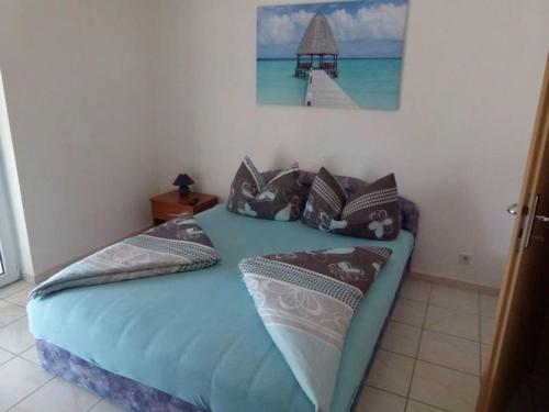 a bed with pillows and a picture of a pier at Apartmani Ivanic in Vir