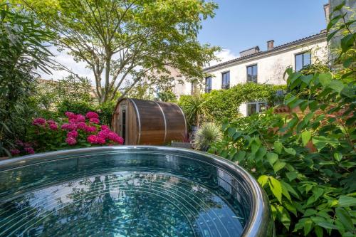 a glass tub in a garden with a barrel at Escale Rochelaise, gîte urbain avec SPA bain nordique et sauna tonneau in La Rochelle