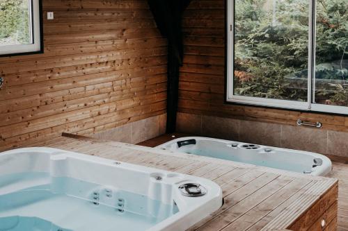 a bathroom with a tub and two windows at Villa Calma - Maison d'hôtes & Spa in Mottier