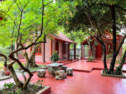 a garden with a building with trees and a brick patio at Tam Family Homestay in Ninh Binh