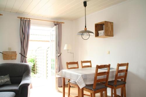 une salle à manger avec une table et des chaises blanches dans l'établissement Wohnung-Schwalbennest, à Süderende