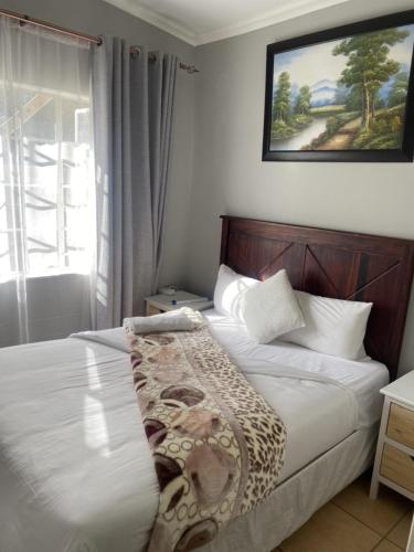a bedroom with a bed with a blanket on it at Menlyn Mews Guesthouse in Pretoria