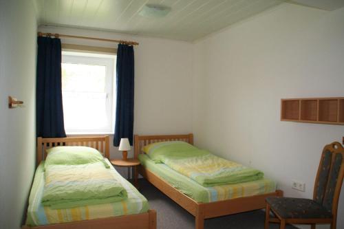 a bedroom with two twin beds and a window at Wohnung-Schwalbennest in Süderende