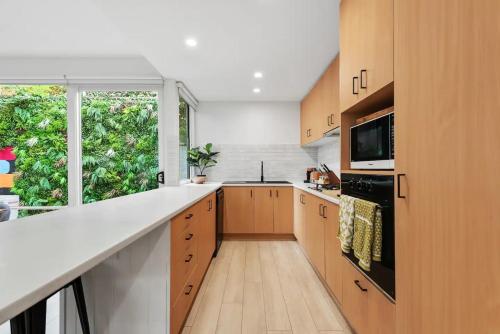 una cocina con armarios de madera y una gran ventana en The Richmond House by Ready Set Stay, en Melbourne